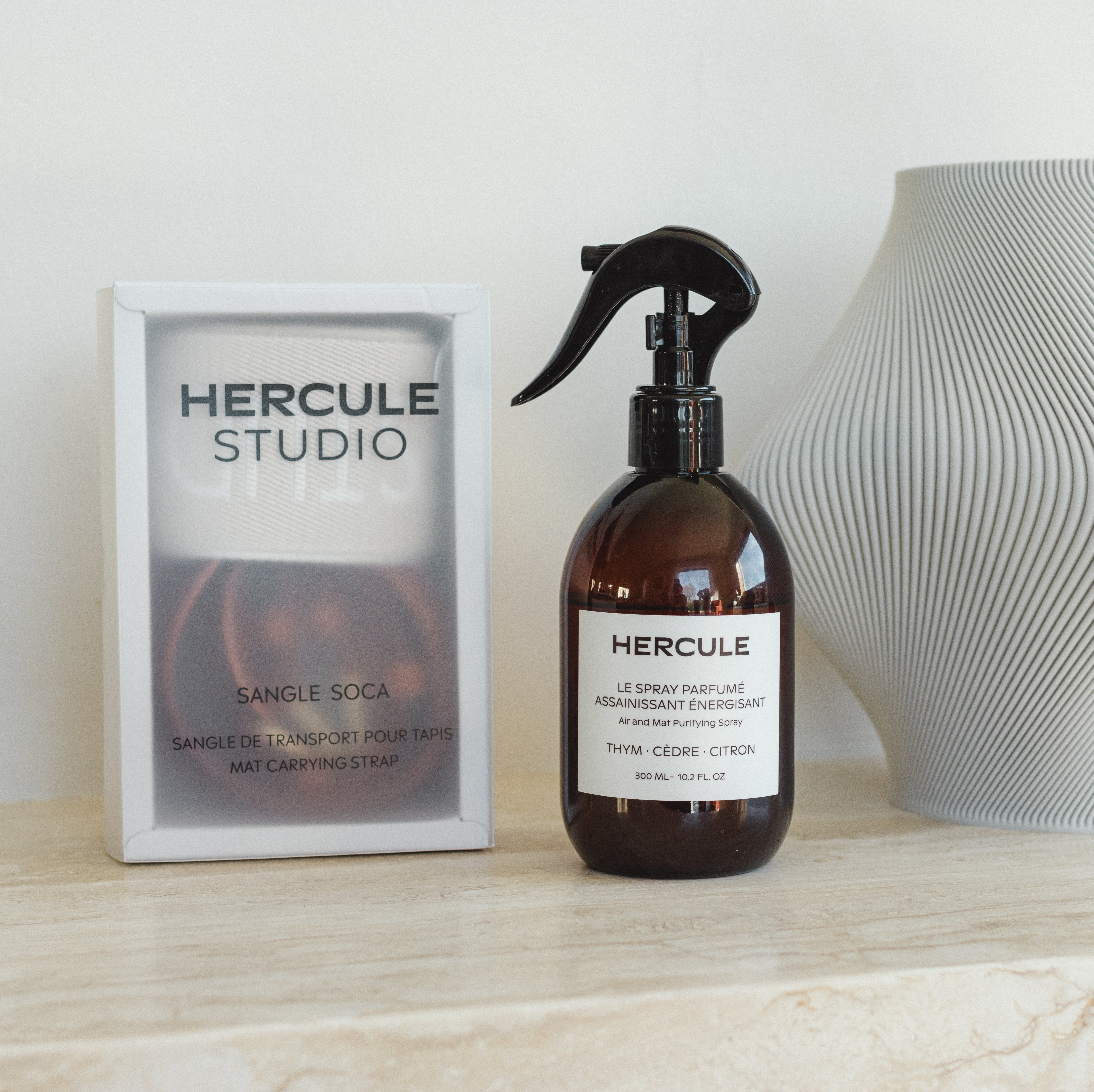 Sangle de transport dans sa boite de rangement et spray parfumé de la marque Hercule Studio photo lifestyle