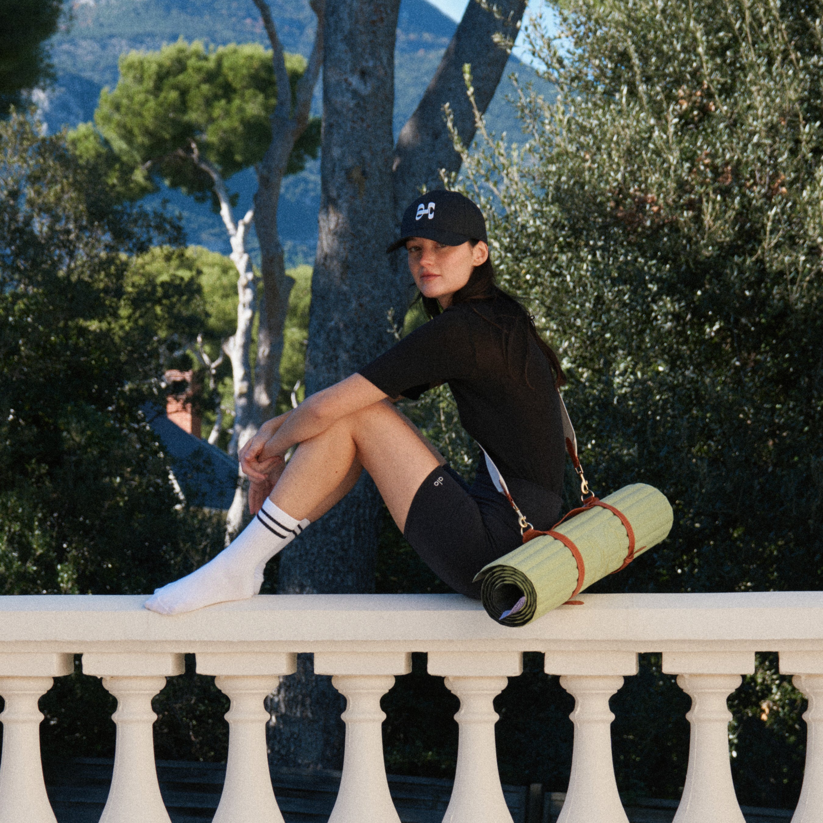 Tapis de sport couleur Pistache de la marque Hercule Studio avec sangle de transport Soca en cuir végétal photo lifestyle avec mannequin sur balcon
