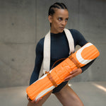 Tapis de sol pour le fitness le yoga et le pilates de la marque hercule studio modèle archy couleur imprimé bari orange pop photo avec un mannequin et sangle de transport soca