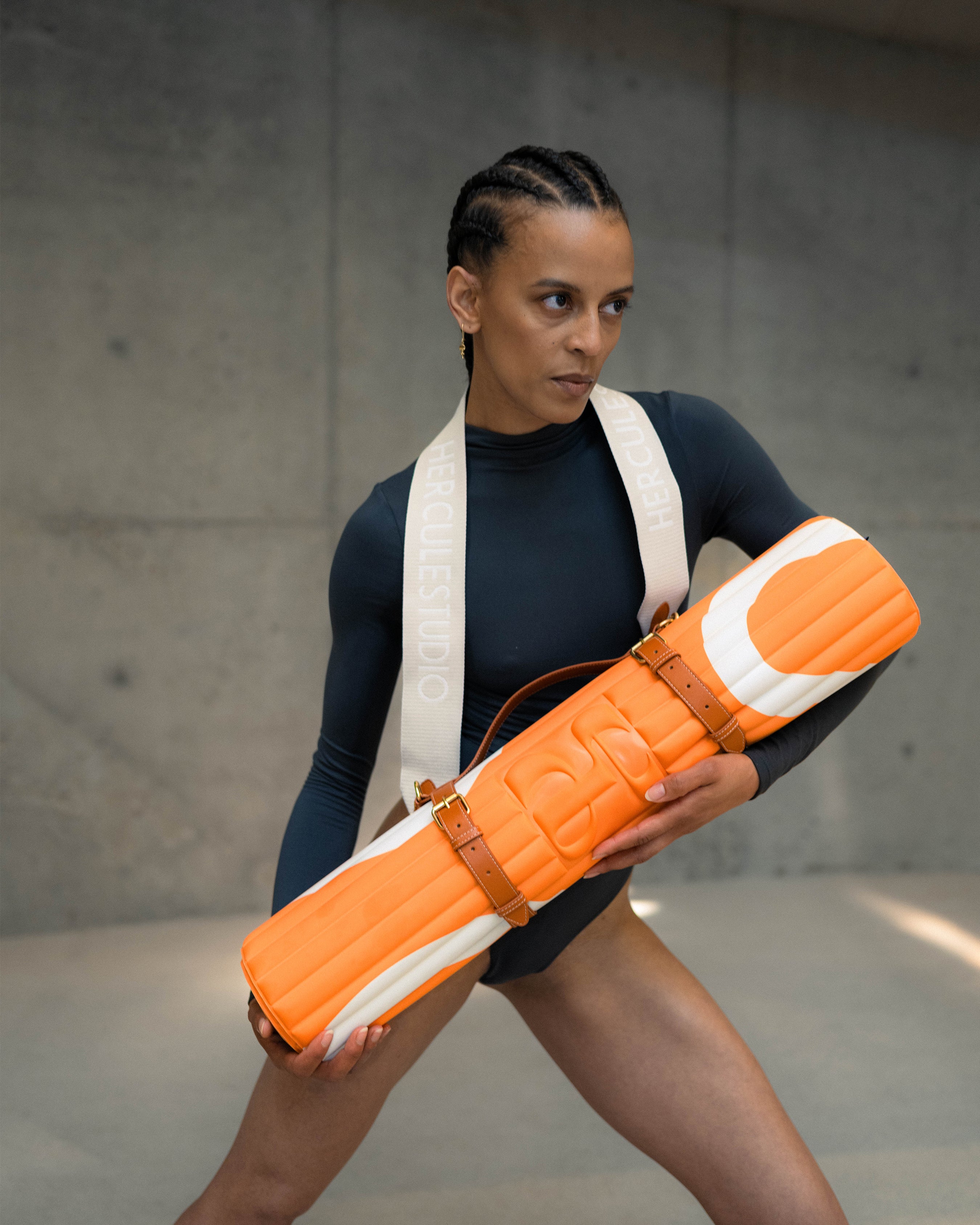 Hercule Studio Archy sport Mat in Orange and Ecru, a premium washable mat for fitness and yoga, complete with a carrying strap for sports mats and a model