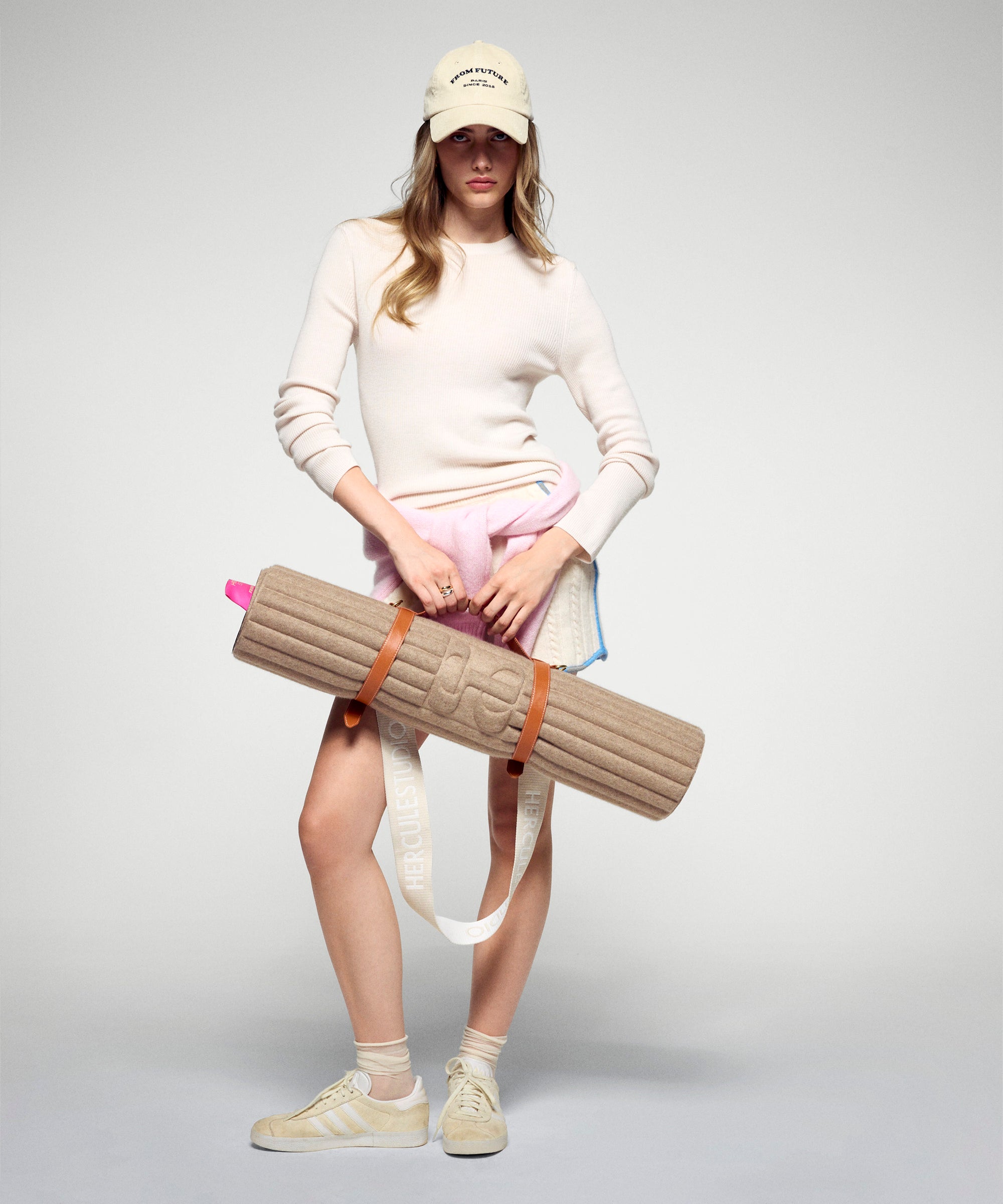 Tapis de sol pour le fitness le yoga et le pilates en cachemire de la marque hercule studio en collaboration édition limitée avec from future modèle archy couleur beige photo lifestyle avec mannequin et sangle de transport soca