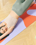 Hercule Studio Archy Axel red orange sport mat in lifestyle session, vibrant graphic print for Pilates and fitness, made in France