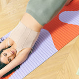 Tapis de sol pour le fitness le yoga et le pilates de la marque hercule studio modèle archy couleur imprimé axel rouge orangé photo avec un mannequin qui fait du sport sur le tapis