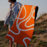 Tapis de sol pour le fitness le yoga et le pilates de la marque hercule studio modèle archy couleur imprimé bari orange pop photo avec un mannequin qui tient le tapis