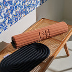 Tapis de sol pour le fitness le yoga et le pilates de la marque hercule studio modèle archy couleur terre cuite photo du tapis roulé à coté du pad de confort noir