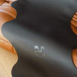 Tapis de sol pour le yoga de la marque hercule studio modèle mar couleur outrenoir photo lifestyle zoom logo photo sur canapé en cuir marron